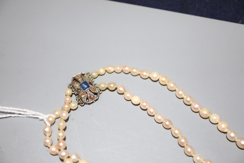 A double strand graduated cultured pearl necklace, with sapphire and diamond set white metal clasp, 70cm.